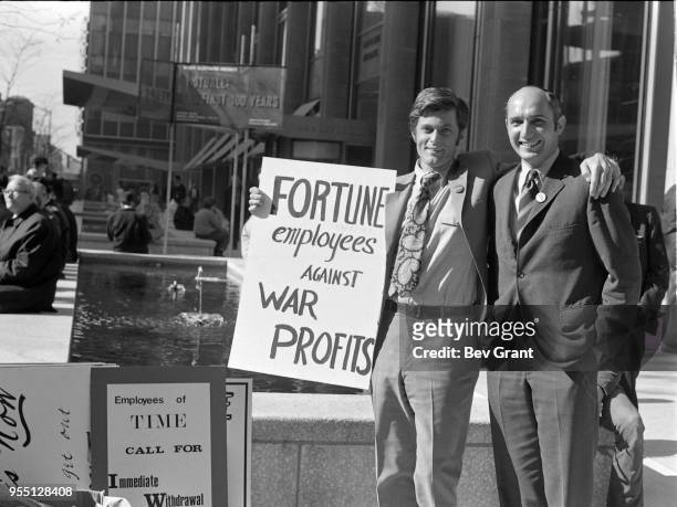 Outside the Time Life Building during the Moratorium to End the War in Vietnam demonstration, two men pose with a sign that reads 'Fortune Employees...
