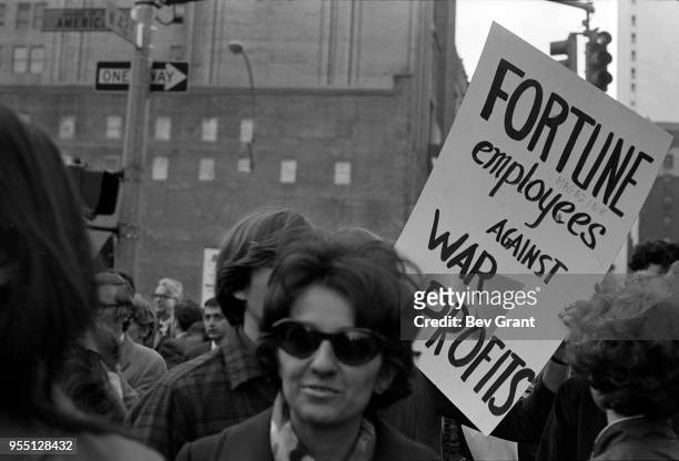View of demonstrators, among pedestrians, as they cross 6th Avenue on West 42nd Street during the Moratorium to End the War in Vietnam demonstration,...