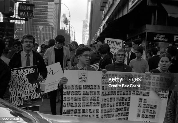 View of demonstrators, among pedestrians, as they cross 49th Street on 6th Avenue during the Moratorium to End the War in Vietnam demonstration, New...
