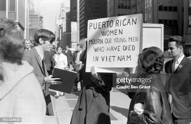 Outside the Time Life Building during the Moratorium to End the War in Vietnam demonstration, a man with a petition talks to a pair of women who hold...