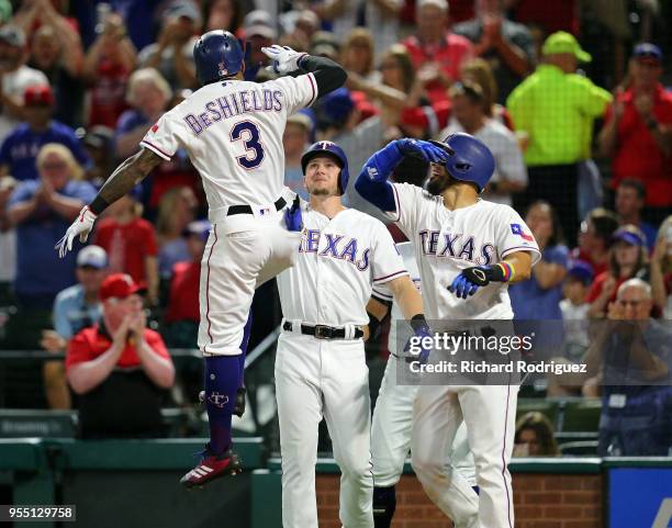 Delino DeShields of the Texas Rangers leaps in the air as he is greeted by Ryan Rua of the Texas Rangers and Robinson Chirinos of the Texas Rangers...