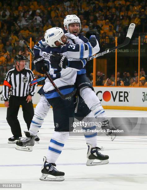 Brandon Tanev of the Winnipeg Jets jumps into the arms of teammate Dustin Byfuglien to congratulate him on scoring a goal against the Nashville...