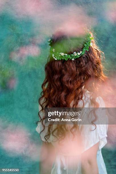 back view of young woman with long wavy red hair wearing white bohemian shirt and flower crown, pastel textured background - pastel hair stock-fotos und bilder