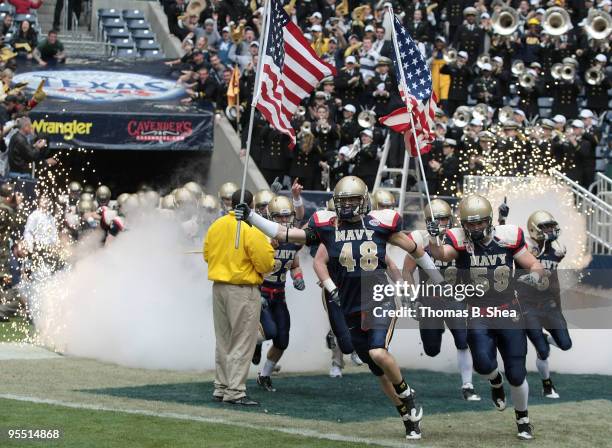 Cameron Marshall and Matt Nechak of the Navy Shipmen carry American flags as the runs onto the field before the Texas Bowl at Reliant Stadium on...