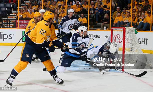 Kevin Fiala of the Nashville Predators takes a backhand shot past Ben Chiarot and wide of goalie Connor Hellebuyck of the Winnipeg Jets during the...