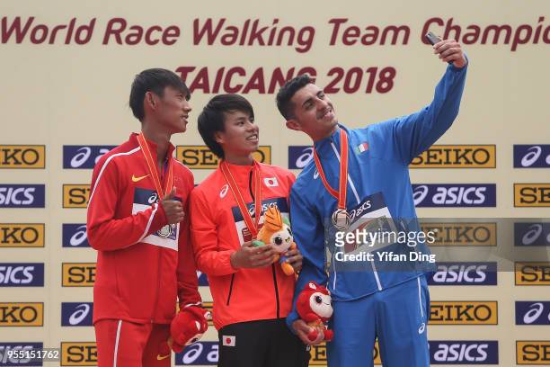 Wang Kaihua of China, Koki Ikeda of Japan and Massimo Stano of Italy take a selfie during medal ceremony of Men's 20 kilometres Race Walk of IAAF...