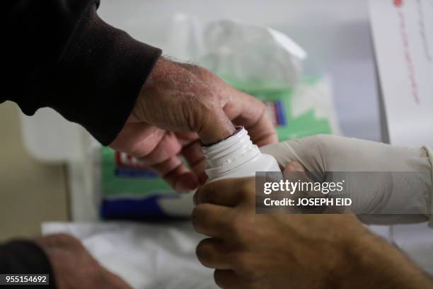 Lebanese man dips his thumb in voting ink after casting his vote in the first parliamentary election in nine years, in the coastal city of Byblos,...