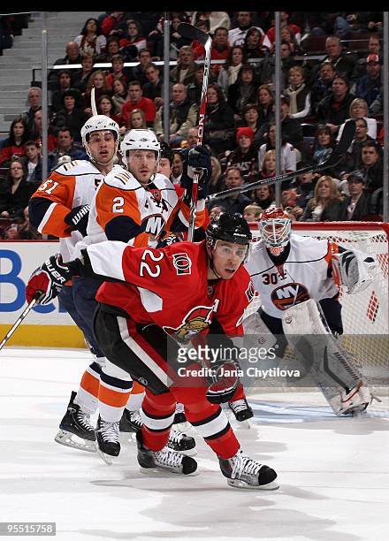 Chris Kelly of the Ottawa Senators turn to skate after the puck as Frans Nielsen and Mark Streit of the New York Islanders defend the net at...