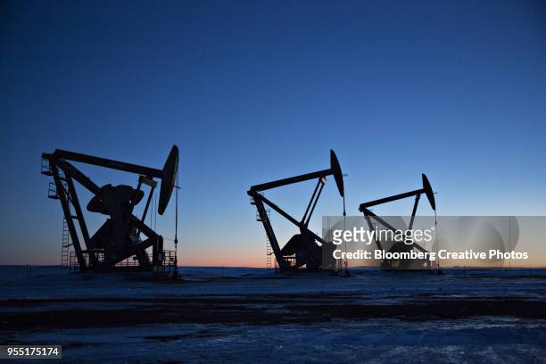 the silhouettes of pumpjacks are seen above oil wells in the bakken formation - oil and gas industry stockfoto's en -beelden