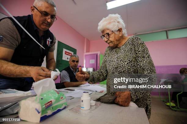 An elderly Lebanese woman dips her thumb in voting ink after casting her vote in the first parliamentary election in nine years, in the Mina district...