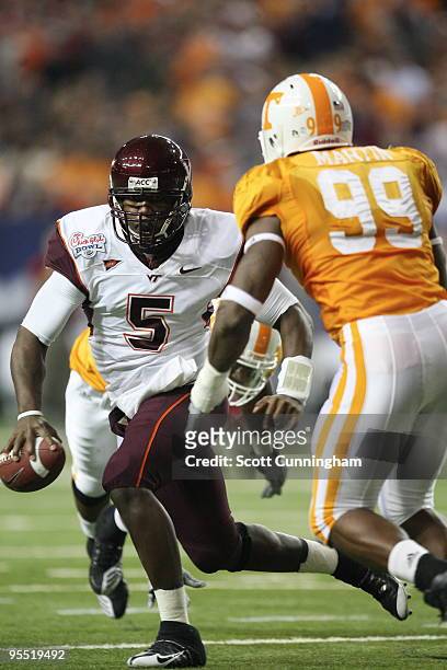 Tyrod Taylor of the Virginia Tech Hokies scrambles during the Chick-Fil-A Bowl game against Ben Martin of the Tennessee Volunteers at the Georgia...