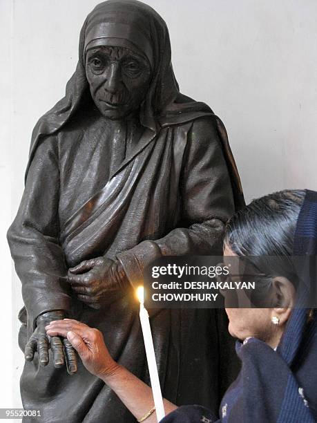 An Indian visitor touches a statue of Mother Teresa while observing prayers at the Missionaries of Charity in Kolkata on January 1, 2010. Nuns,...