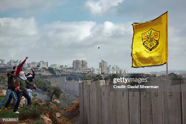 Palestinians hurl stones at Israeli troops on the other side of Israel's controversial separation barrier during a Fatah Day protest on January 1,...
