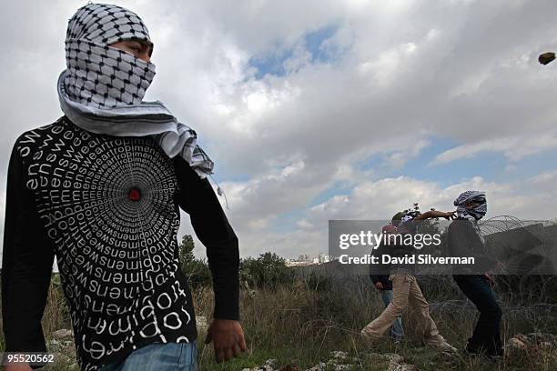 Palestinians hurl stones at Israeli troops on the other side of Israel's controversial separation barrier during a Fatah Day protest on January 1,...