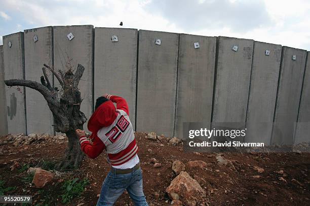Palestinian throws stones at Israeli troops on the other side of Israel's controversial separation barrier during a Fatah Day protest on January 1,...