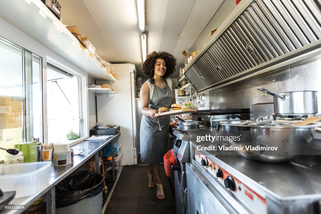 African woman cooking inside of food truck
