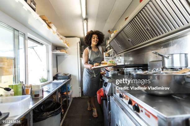 african woman cooking inside of food truck - food truck street stock pictures, royalty-free photos & images