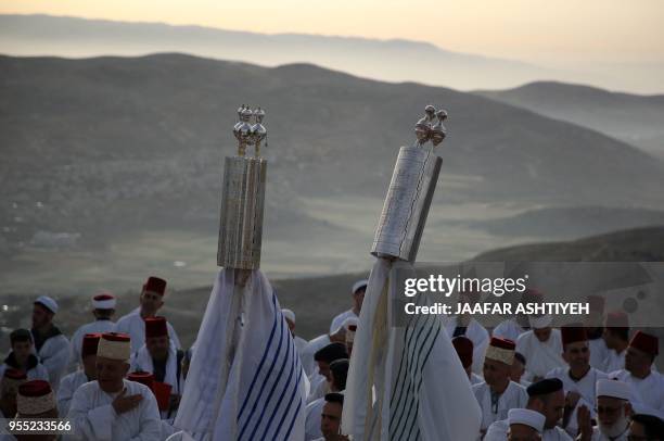 Samaritan worshippers raise a Torah scroll as they pray during a Passover ceremony at Mount Gerizim near the northern West Bank city of Nablus, on...