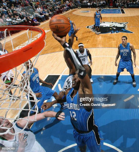 Dwight Howard of the Orlando Magic fights for the rebound against Al Jefferson and Kevin Love of the Minnesota Timberwolves during the game on...