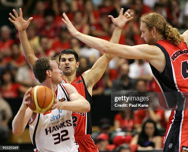 Luke Schenscher and Kevin Lisch of the Wildcats hold out Mat Campbell of the Hawks during the round 14 NBL match between the Perth Wildcats and the...