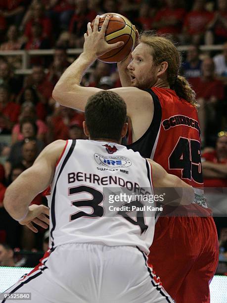 Luke Schenscher of the Wildcats looks for a pass around Tim Behrendorff of the Hawks during the round 14 NBL match between the Perth Wildcats and the...