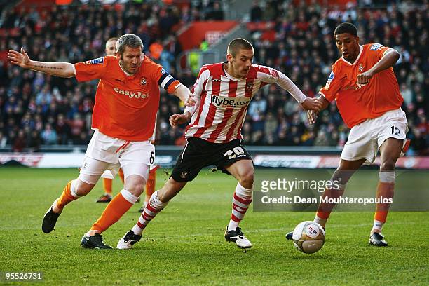 Adam Lallana of Southampton battles for the ball with Kevin Nicholls and Shane Blackett of Luton Town during the third round match of The FA Cup,...