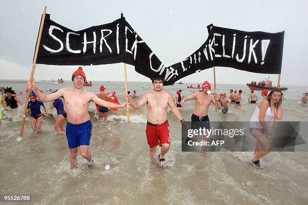 People carry a sign as they wade in the North Sea during a traditional New Year's dive in Oostende on January 2, 2010. AFP PHOTO/BELGA/KURT DESPLENTER