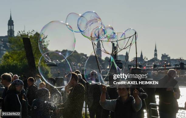 Woman makes giant soap bubbles at the Fischmarkt on the banks of the river Elbe in Hamburg, northern Germany, on May 6, 2018. / Germany OUT