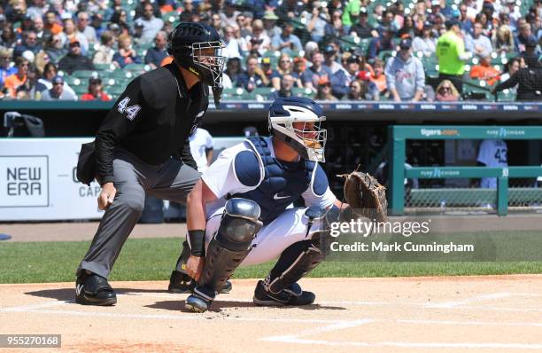Catcher James McCann of the Detroit Tigers and Major League umpire Kerwin Danley crouch behind home plate during the game against the Kansas City...