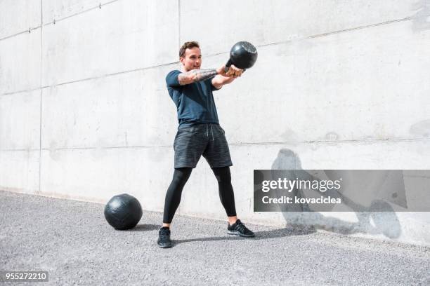 man exercising with a kettlebell outdoors - kettle bell stock pictures, royalty-free photos & images