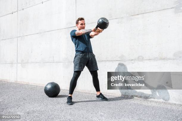 man exercising with a kettlebell outdoors - kettlebell imagens e fotografias de stock