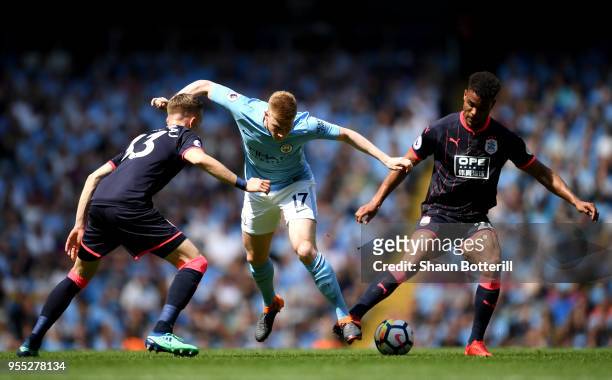 Kevin De Bruyne of Manchester City is challenged by Florent Hadergjonaj of Huddersfield Town and Steve Mounie of Huddersfield Town during the Premier...