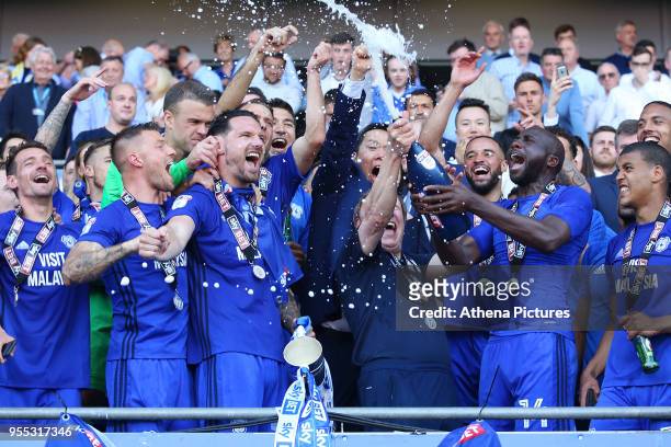 Sean Morrison of Cardiff City lifts the trophy as Sol Bamba sprays champagne over Cardiff City manager Neil Warnock and Cardiff as they celebrate...