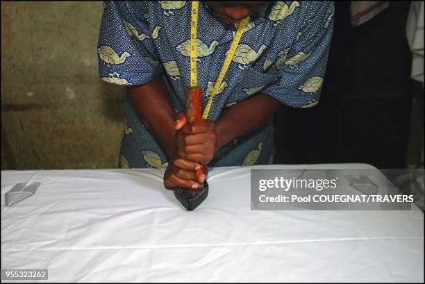 Rafiou Waliou Adewale uses wooden stamps covered with hot wax to mark the cloth with specific patterns.