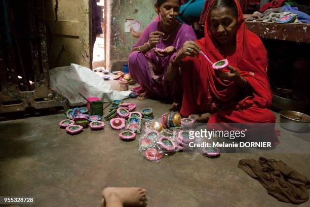 Une femme peint avec précision des diyas dans la seule pièce qui lui sert de maison, New Delhi, Inde.