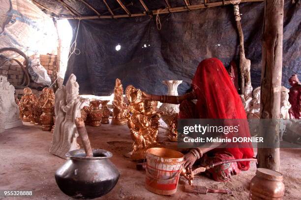 Les femmes et les enfants travaillent à la peinture des icones religieuses, New Delhi, Inde. Les maigres revenus de la vente feront survivre la...