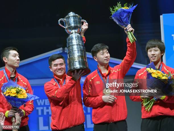 China's team members pose with their trophy on the podium after winning over Germany their men's final at the World Team Table Tennis Championships...