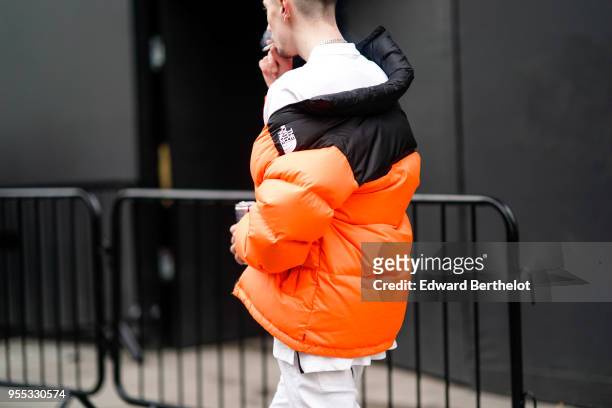 Guest wears an orange puffer coat, during London Fashion Week Men's January 2018 at on January 6, 2018 in London, England.