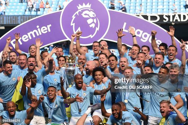 Manchester City's Spanish manager Pep Guardiola holds the Premier League trophy on the pitch with Manchester City players after the English Premier...