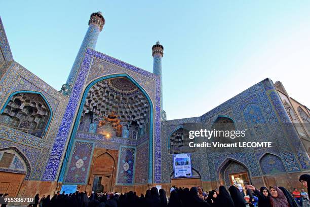 Vue de la façade de la grande mosquée du Chah à Ispahan, Iran, derrière un groupe de femmes voilées de noir, en avril 2015.