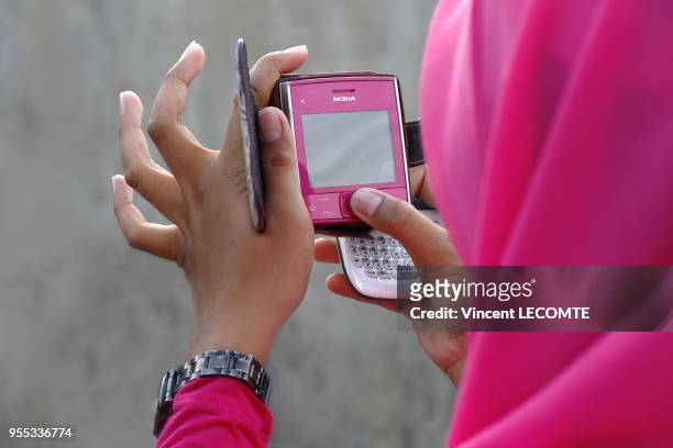 Adolescente indonésienne voilée écrivant un sms sur son smartphone à Painan, au sud de l?île de Sumatra, en Indonésie, en septembre 2012.
