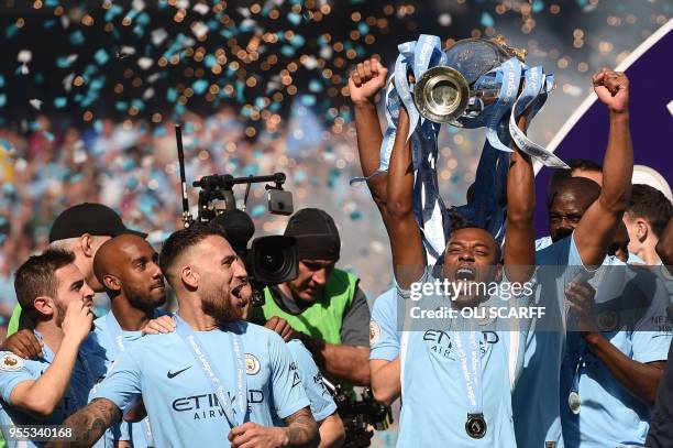 Manchester City's Brazilian midfielder Fernandinho holds the Premier League trophy on the pitch after the English Premier League football match...