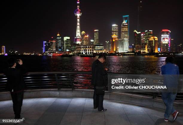 Des touristes chinois visitent et photographient de nuit les grattes ciels illuminés de Pudong, le célèbre quartier d'affaires de la ville le 1 Avril...