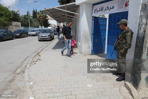 An armed Tunisian soldier stands guard outside a primary school turned into a polling station during the municipal election, as Tunisian voter and a...