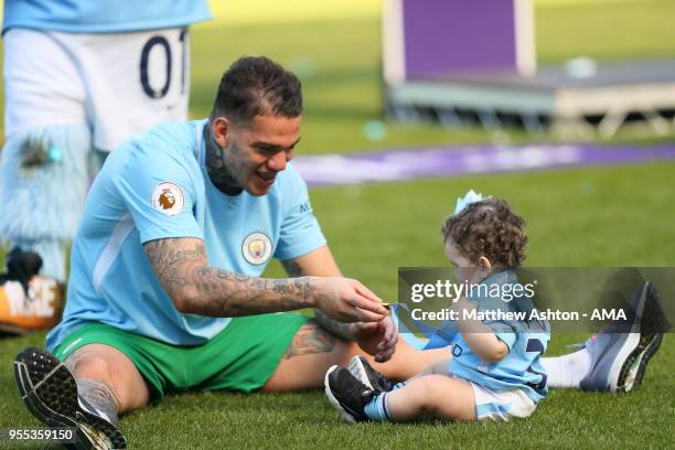 Goalkeeper Ederson Moraes of Manchester City puts his medal around his daughter Yasmin during the championship celebrations after the Premier League...