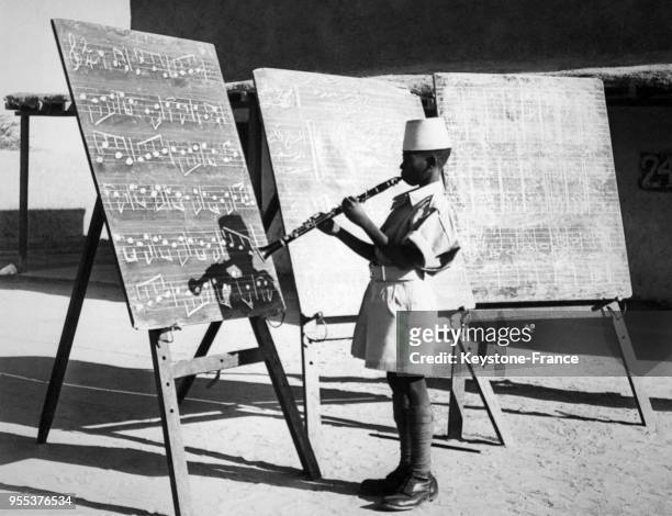 Un très jeune membre des forces de défense soudanaise joue de la clarinette devant un tableau comportant des partitions au dépôt militaire à...