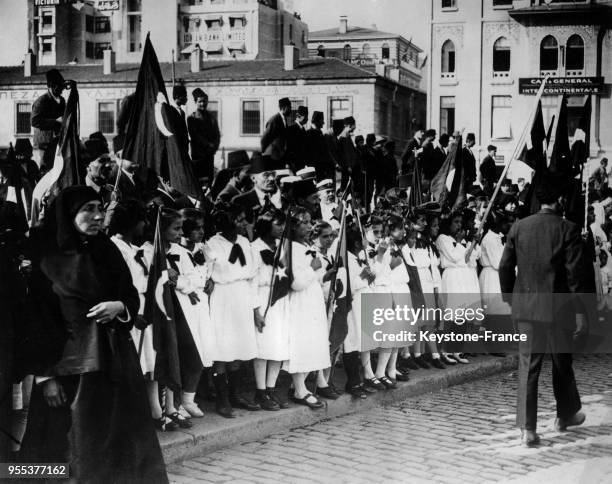 Des petites filles vêtues de leur uniforme scolaire sont alignées sur le trottoir en attendant la visite du général Refet Pasha, à Constantinople,...