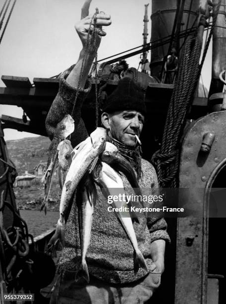 Un pêcheur vend ses poissons du jour directement depuis sa barque sur l'île de Barra, dans les Hébrides Extérieures, à Castlebay, Royaume-Uni.