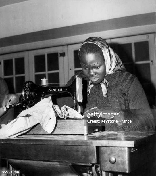 épouse d'un dignitaire soudanais apprend à se servir d'une machine à coudre dans le cadre de son séjour anglais avec d'autres femmes africaines pour...