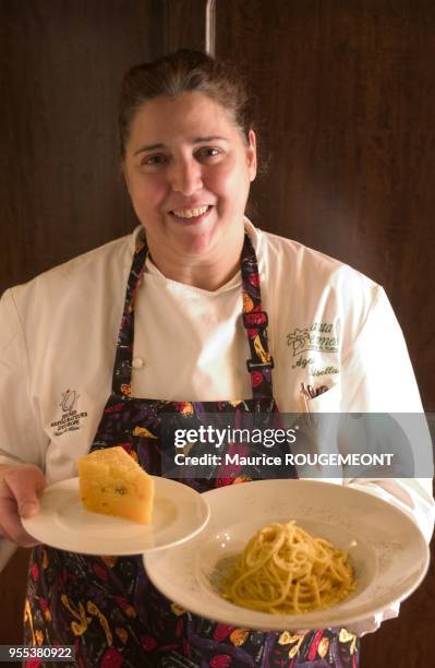 Agata Parisella tient dans une main une assiette contenant des spaghettis au poivre et dans l'autre du fromage fort.